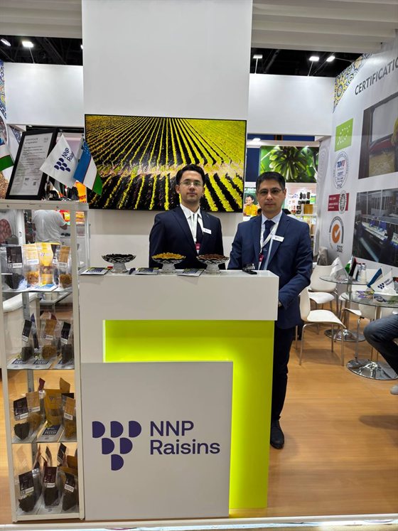Two NNP Raisins colleagues at the stand counter at Gulfood 2025, the range in bowls in front of them.