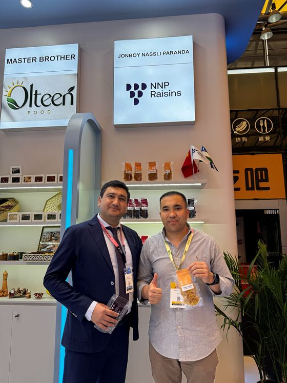 The NNP Raisins stand at SIAL Shanghai 2026, two colleagues in front of the lit fascia sign.